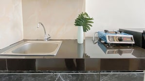 A kitchen with a sink, a stove, and two potted plants. - Basic Studio Apartment Near Cisauk Station At Serpong Garden (Cisauk)