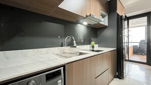 Ett modernt kök med en inbyggd diskmaskin, en diskho med blandare och en liten krukväxt på bänkskivan.