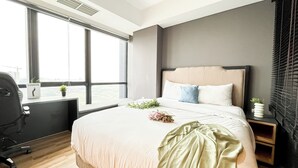 Ett modernt hotellrum med en stor säng, ett skrivbord och utsikt över staden.