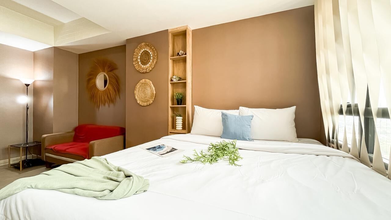 Ein Hotelzimmer mit einem Bett, einem roten Sessel, einer Holzwand mit Dekoration und einem Fenster mit Vorhängen.