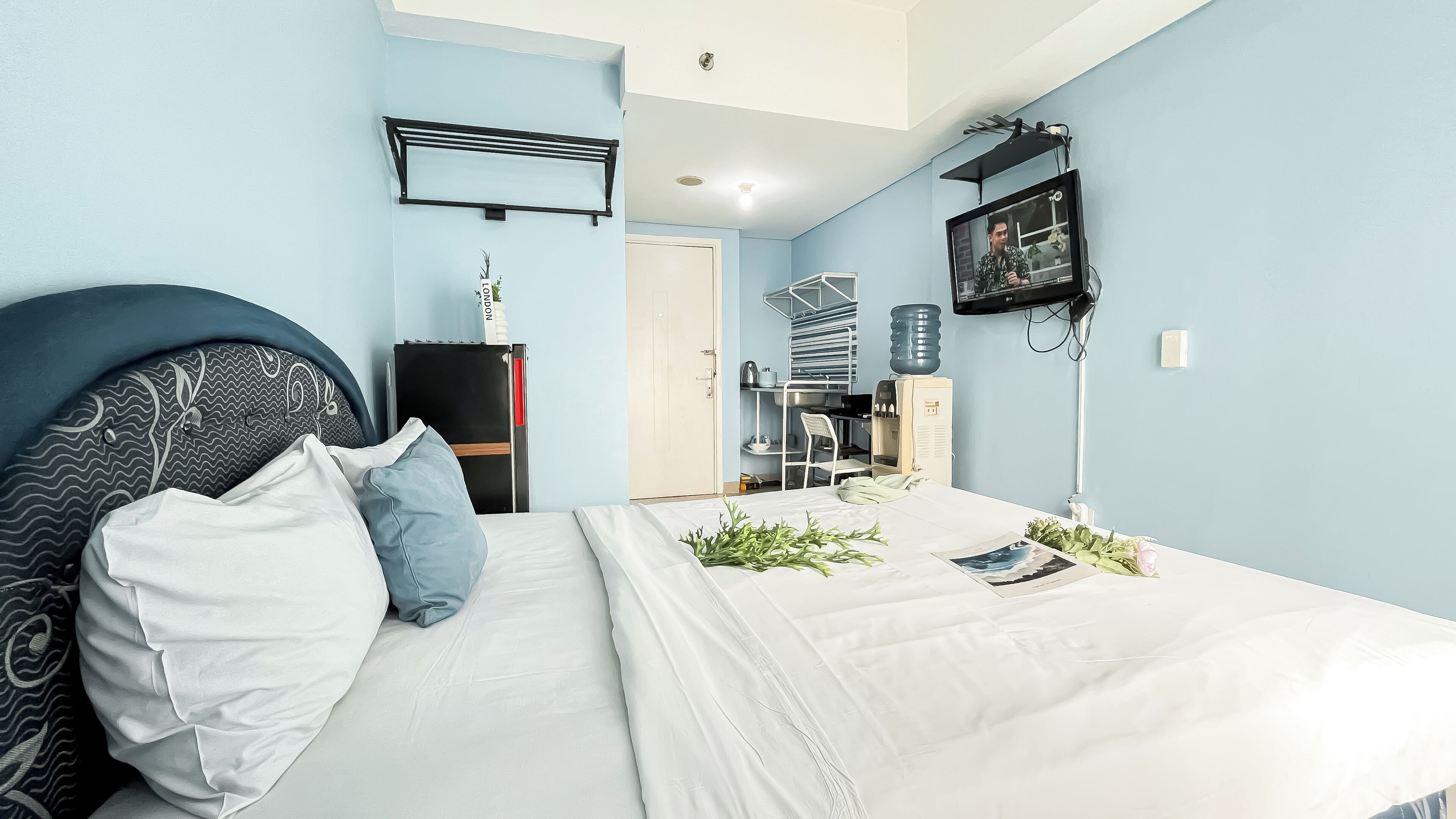 Une chambre à coucher avec un lit, une télévision, un bureau et une armoire.