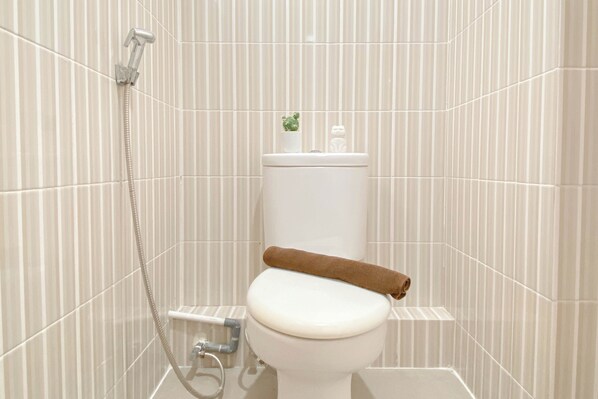 A bathroom with a toilet, a shower, and a towel rack. - Minimalist Studio Apartment At Cinere Resort (Depok)