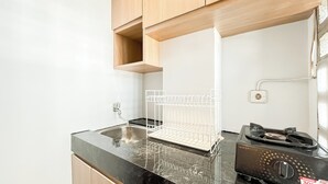 A kitchen with a black countertop, a stainless steel sink, a white drying rack, and a gas stove.