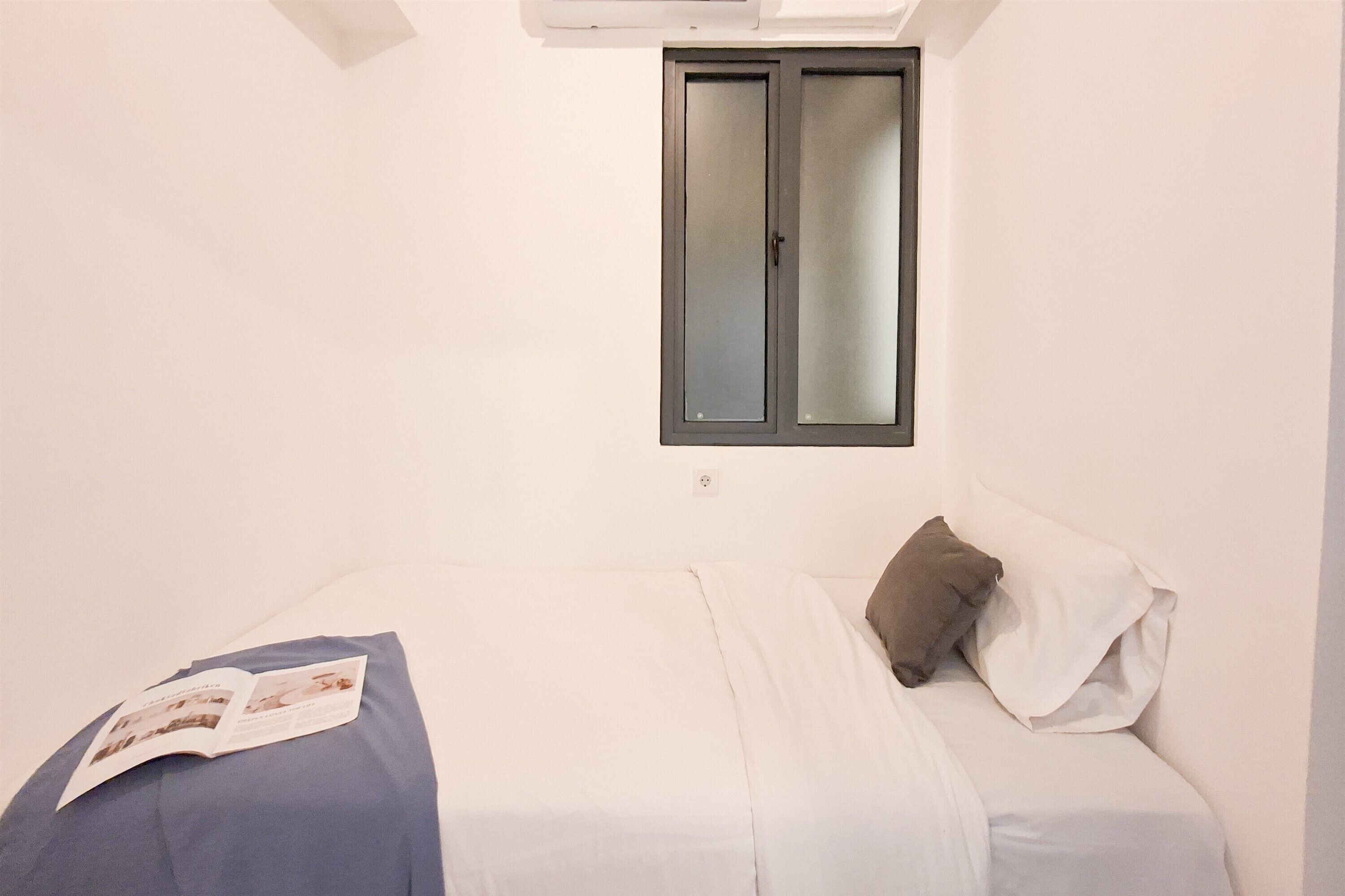 A bedroom with a bed, a window, and a wall-mounted air conditioning unit.