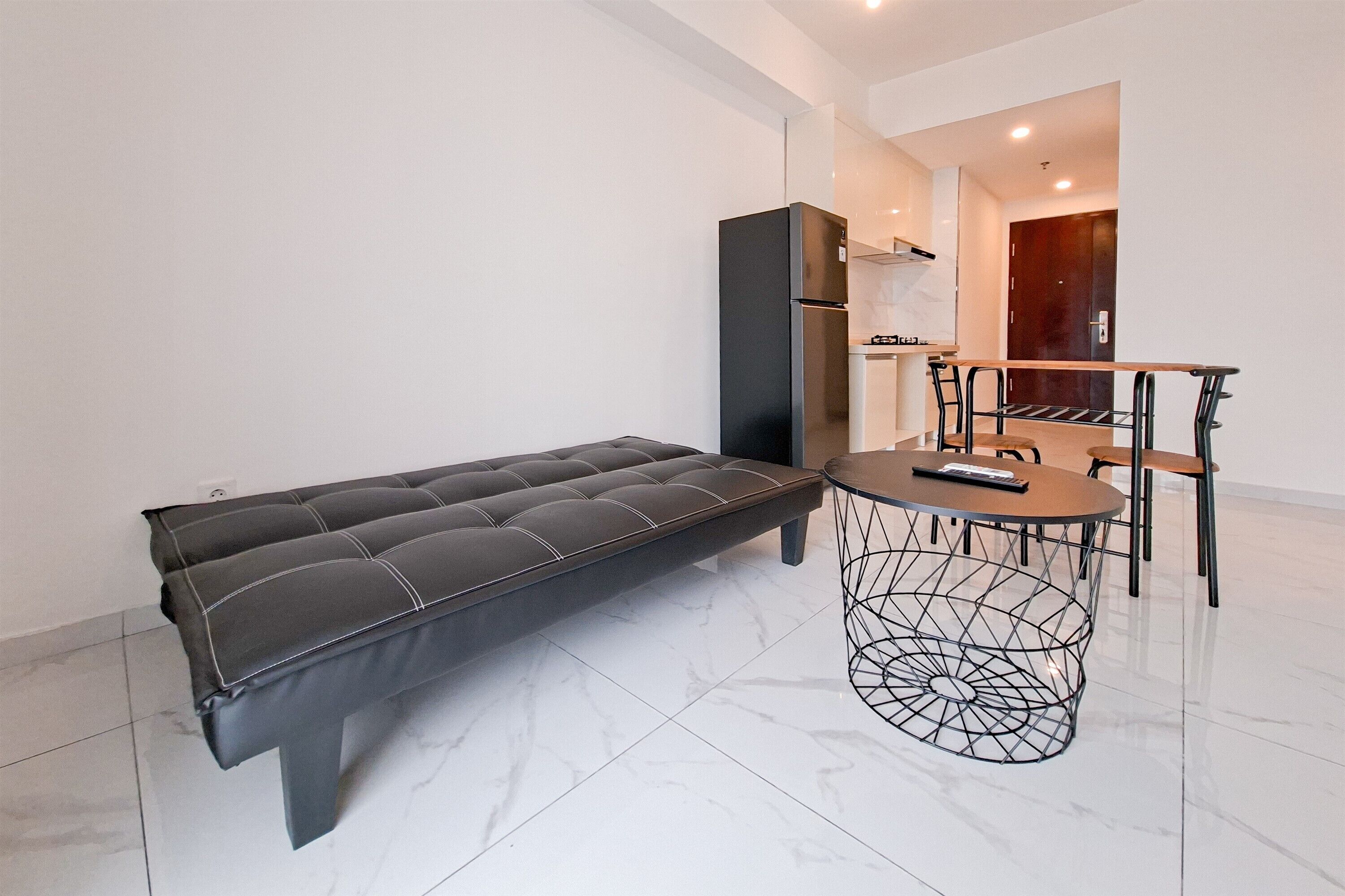 Uma sala de estar moderna com um sofá, uma mesa de centro redonda e um espaço de jantar com cadeiras.
