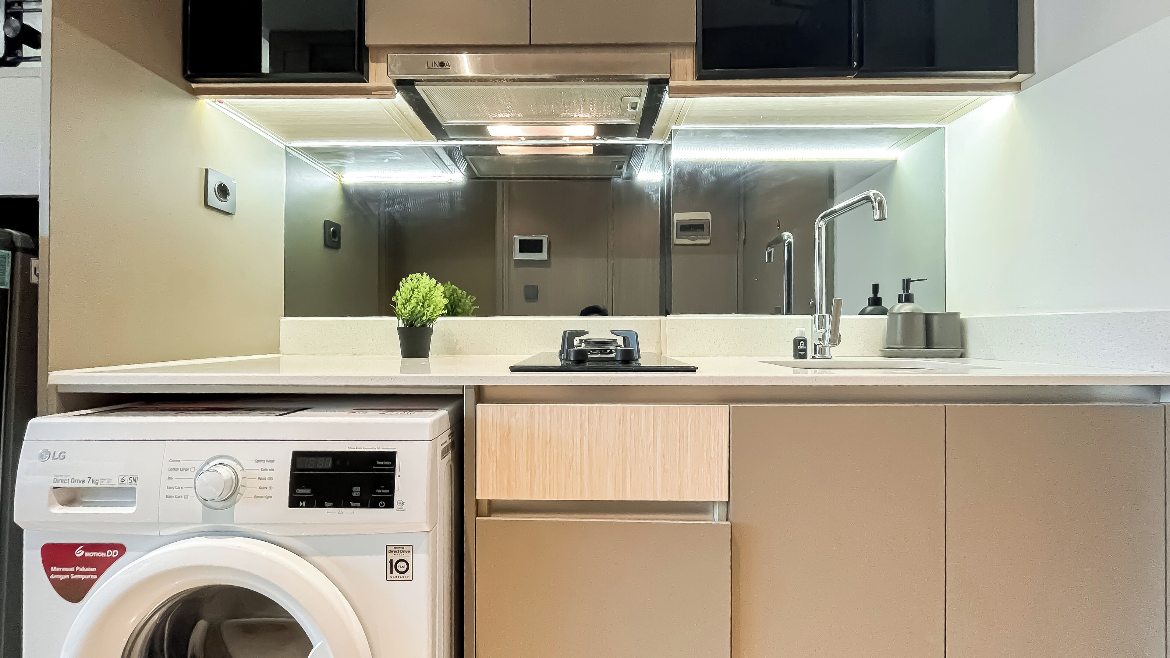 A compact kitchen with a built-in washing machine, a microwave, and a sink with a faucet.