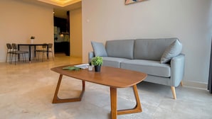 A modern living room with a grey sofa, a wooden coffee table, and a dining area with chairs and a table.