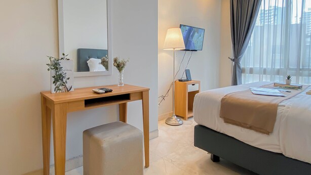 A modern hotel room with a bed, a desk, a chair, a TV, and a window with curtains.