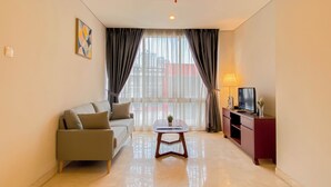 A modern living room with a sofa, a coffee table, a TV on a stand, and a window with curtains.