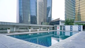 A swimming pool with a modern design, surrounded by a low wall and potted plants.