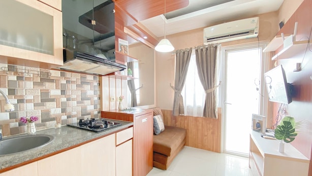 A compact kitchen with a sink, stove, and a small dining area. - Simple Style 2Br At Green Pramuka City Apartment (Jakarta)