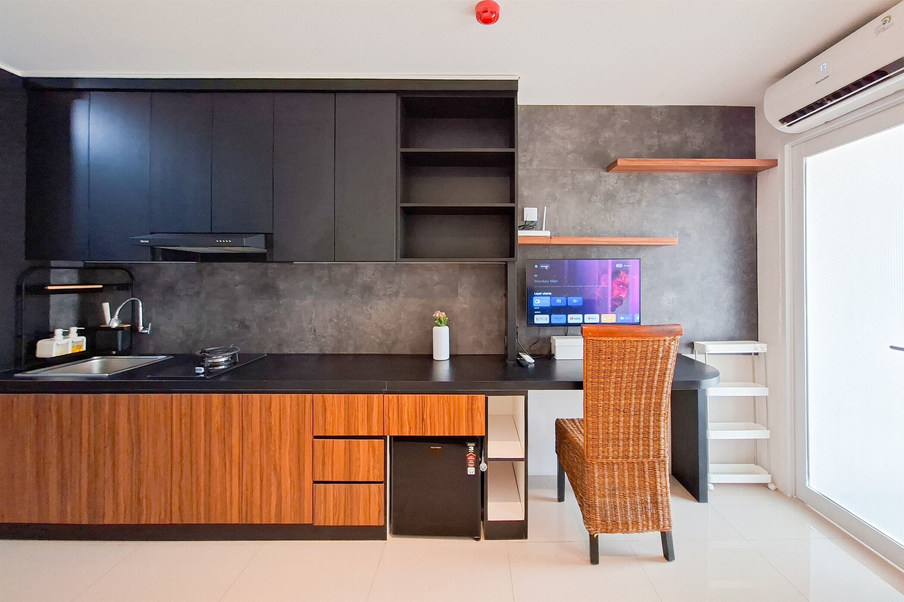 A modern kitchen with a wooden island, dark cabinets, and a built-in TV.