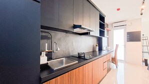Une cuisine moderne dotée d’un plan de travail noir, de meubles en bois, d’un évier en acier inoxydable et d’une cuisinière encastrée.