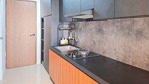 Une cuisine moderne avec un plan de travail noir, un évier en acier inoxydable et des armoires en bois.