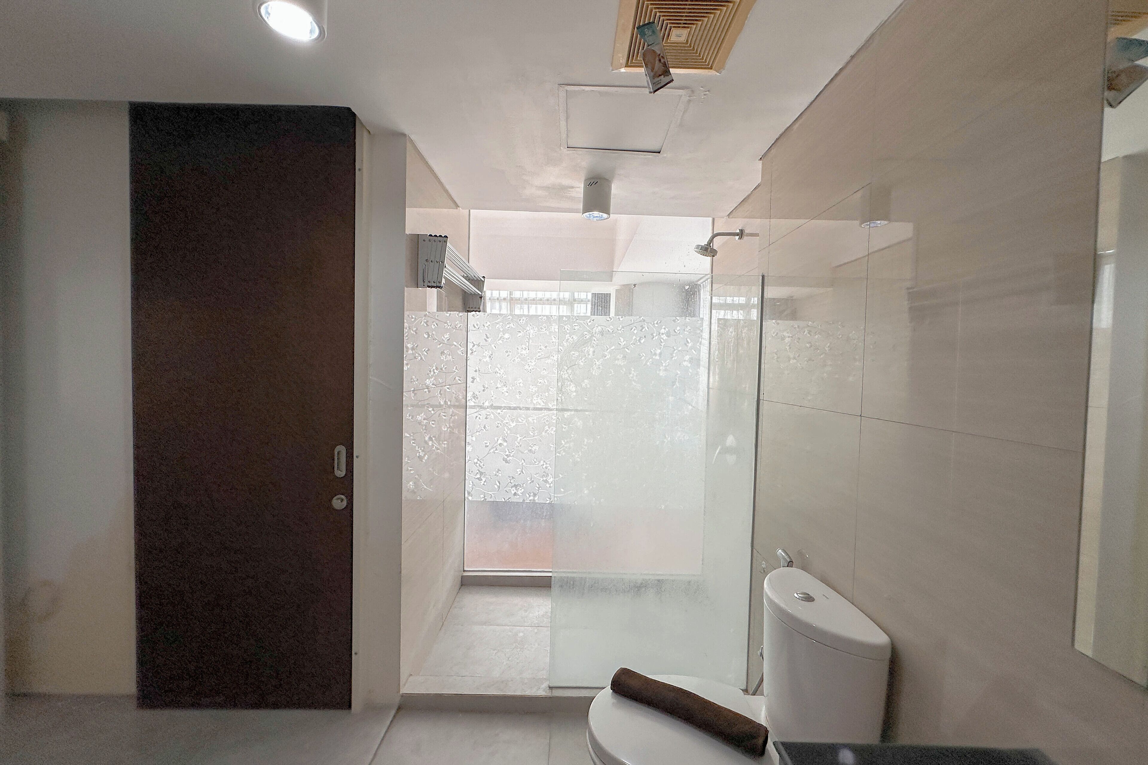 Un bany modern amb un plat de dutxa de vidre, un vàter i una porta fosca.