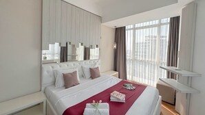 Ein Hotelzimmer mit einem großen Bett, einem Nachttisch, einem Spiegel und einem Fenster mit Vorhängen.