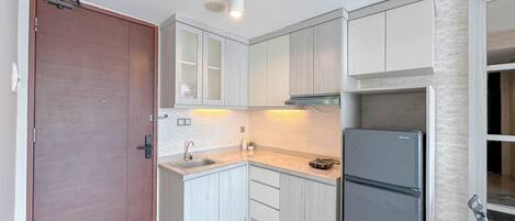 A compact kitchen with white cabinets, a double-door refrigerator, and a sink.