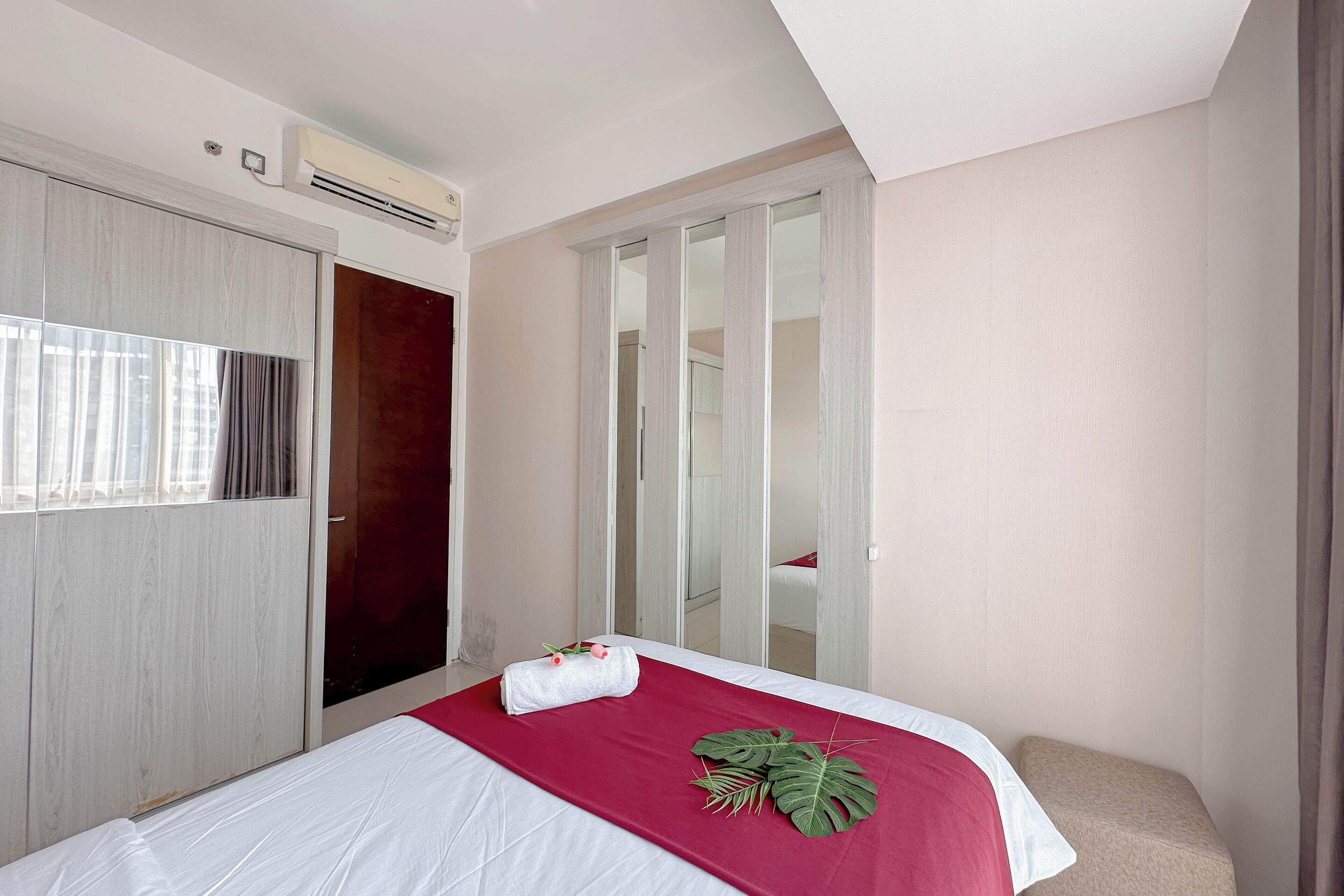 Een hotelkamer met een bed, een kledingkast, een spiegel en een airconditioner.