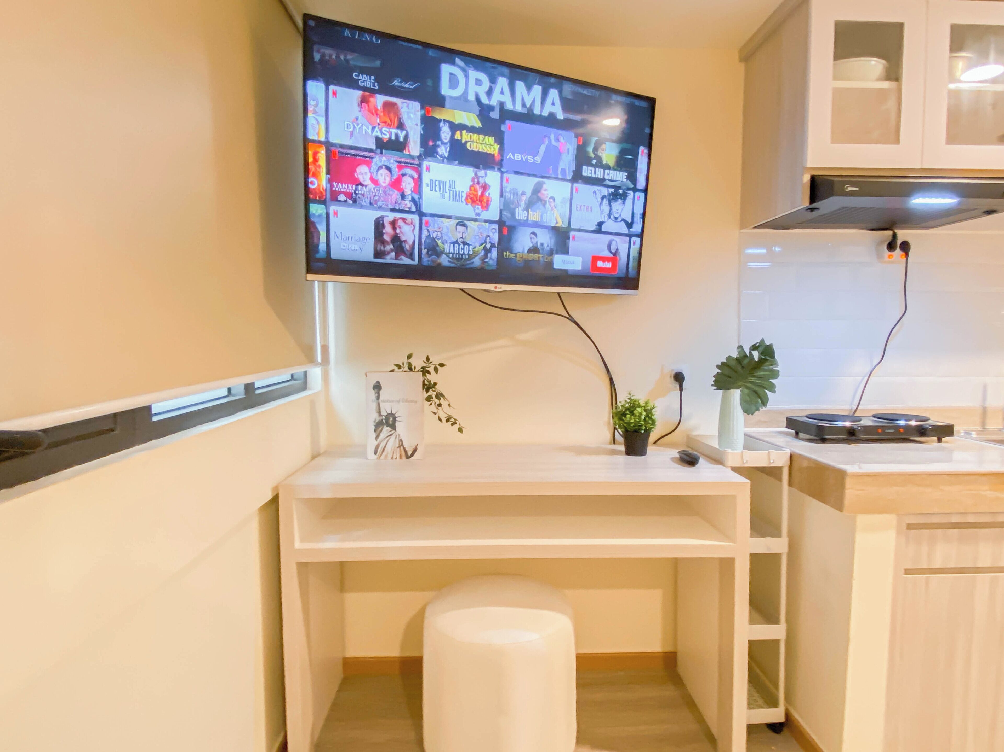 A modern kitchen with a flat-screen TV mounted above a white countertop, displaying a variety of streaming services.