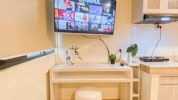 A modern kitchen with a flat-screen TV mounted above a white countertop, displaying a variety of streaming services.