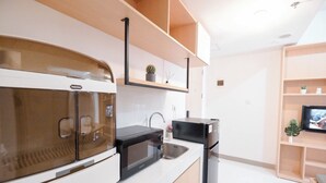 A modern kitchen with white cabinetry, a built-in oven, a microwave, and a refrigerator.