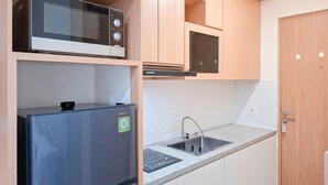 A kitchen with a microwave, a built-in oven, a sink, and a refrigerator. - Urban Minimalist Studio Apartment At B Residence (Pagedangan)