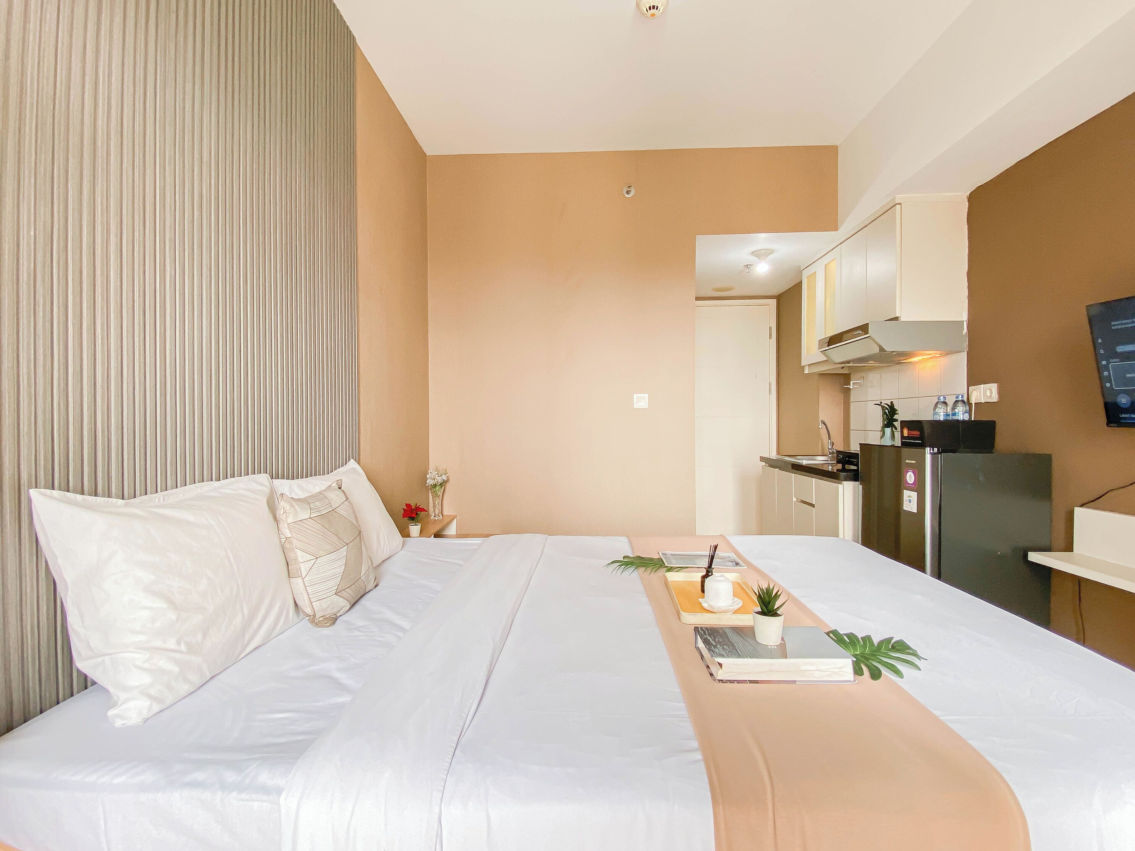 Habitación de hotel con cama, mesita de noche y zona de kitchenette.