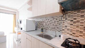 A modern kitchen with a stainless steel sink, a black stove, and a tiled backsplash. - Strategic Studio Apartment Signature Park Grande Near Ciliwung Lrt Station (Jakarta)