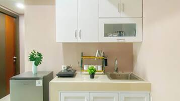 A compact kitchen with white cabinets, a sink, and a small refrigerator.