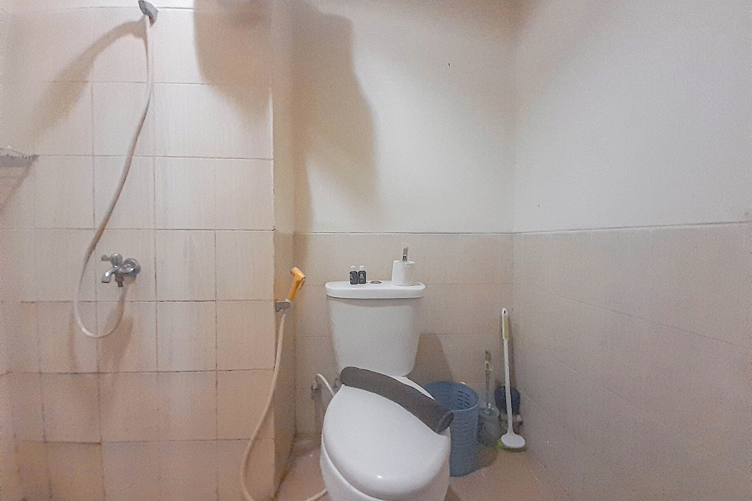 Et lille badeværelse med toilet, bruser og vask.