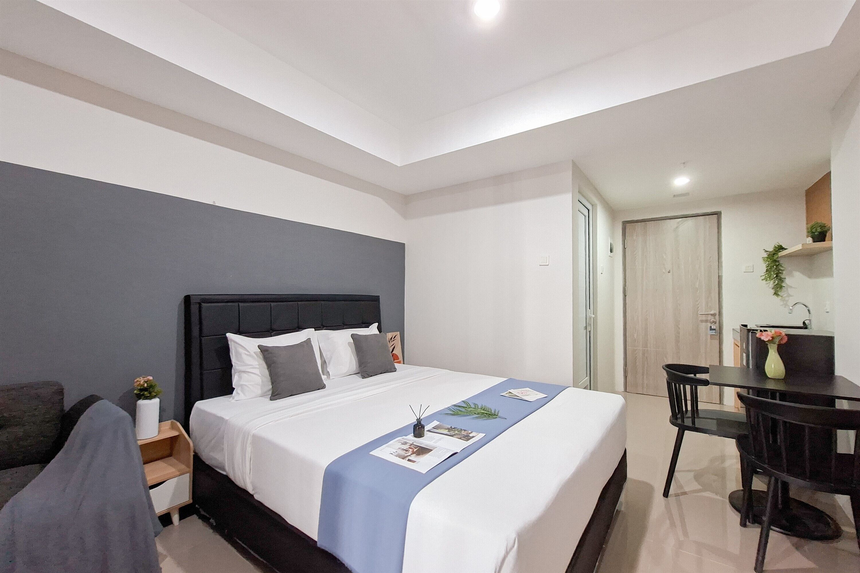 A modern hotel room with a large bed, a desk, and a chair.