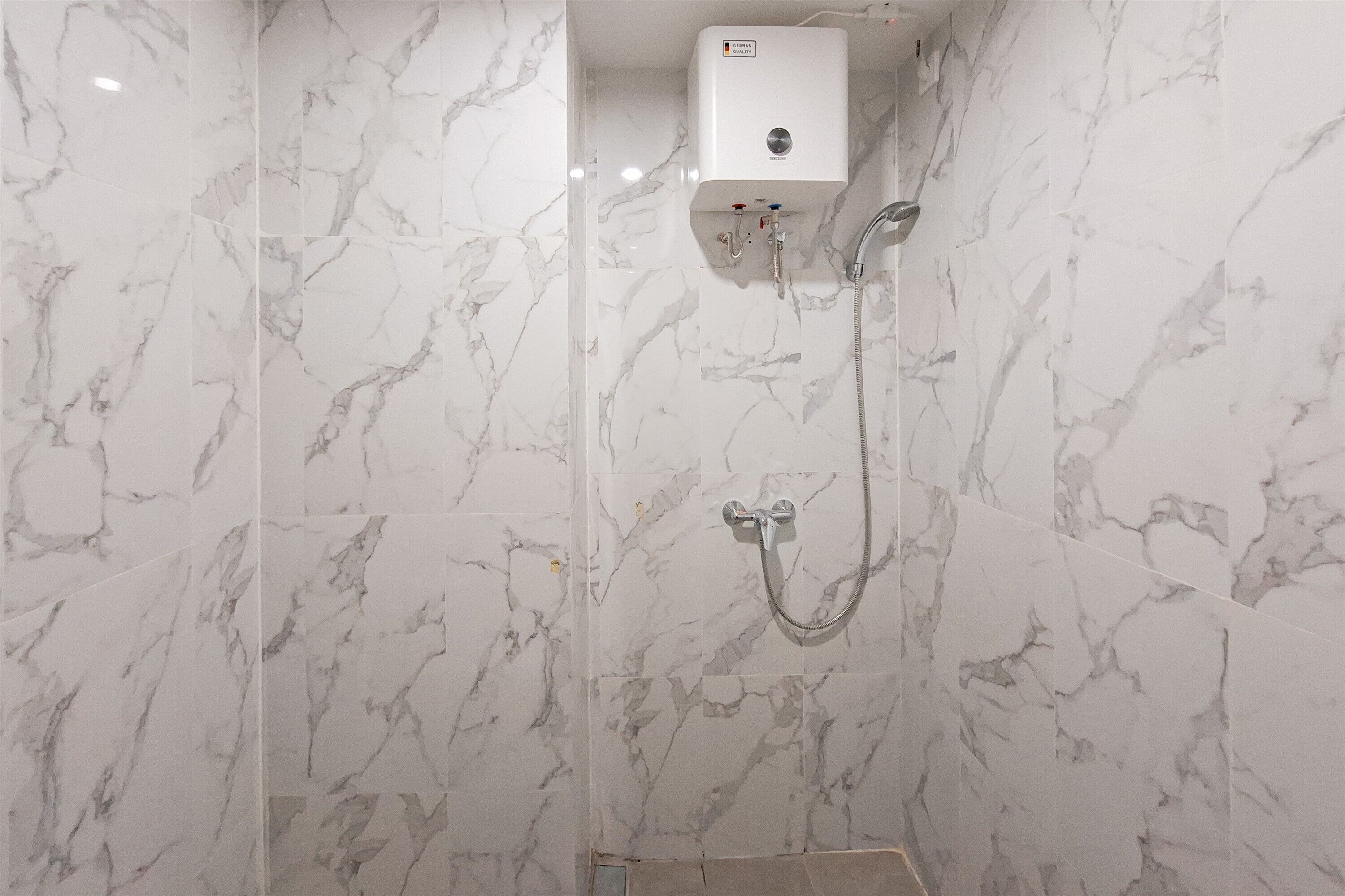 A bathroom with marble walls and a built-in shower unit.