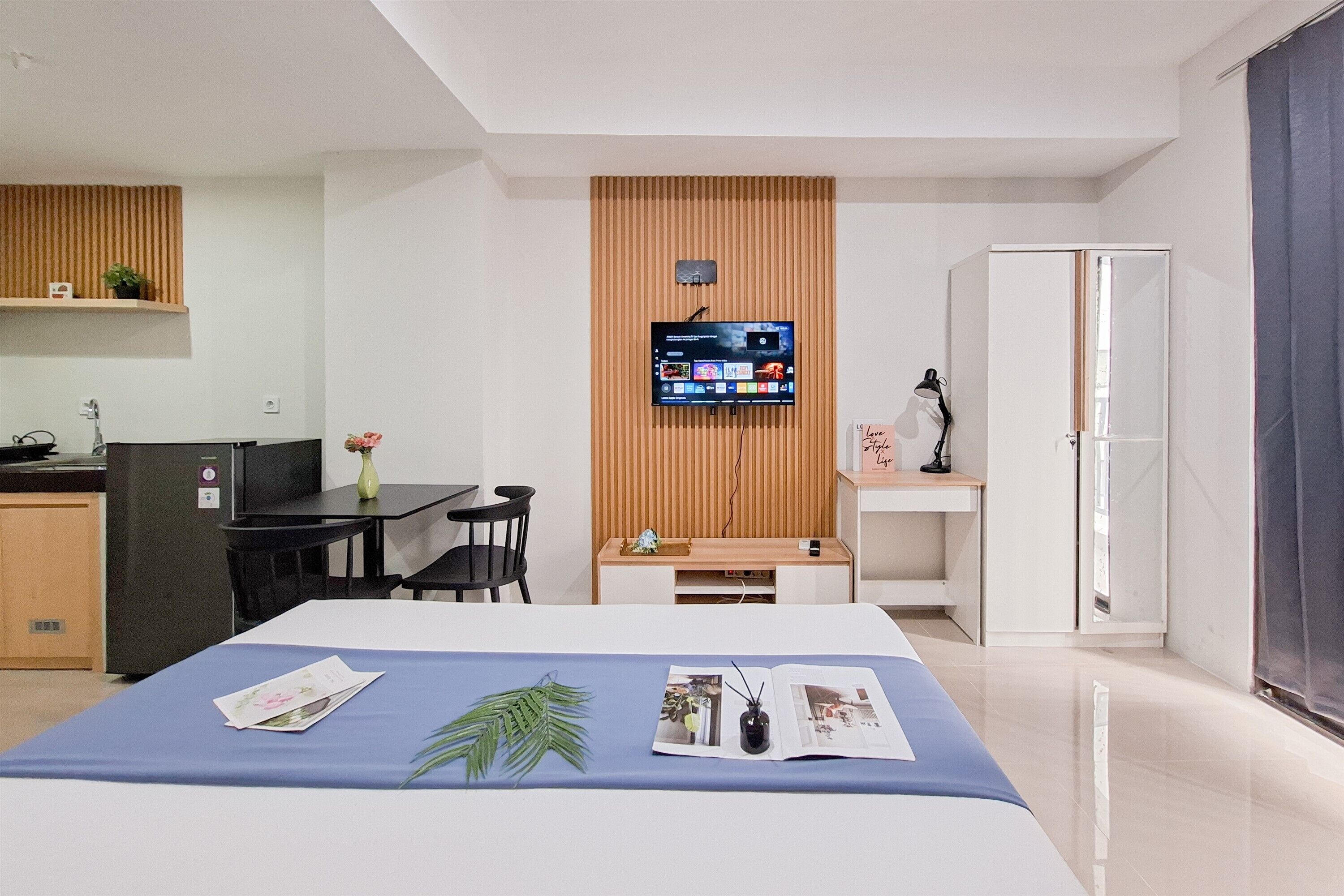 A modern hotel room with a bed, a desk, a TV, and a wardrobe.