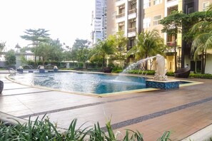 A swimming pool with a water fountain, surrounded by palm trees and a tiled walkway. - Big And Combined 3Br Apartment Silkwood Residence (Tangerang)