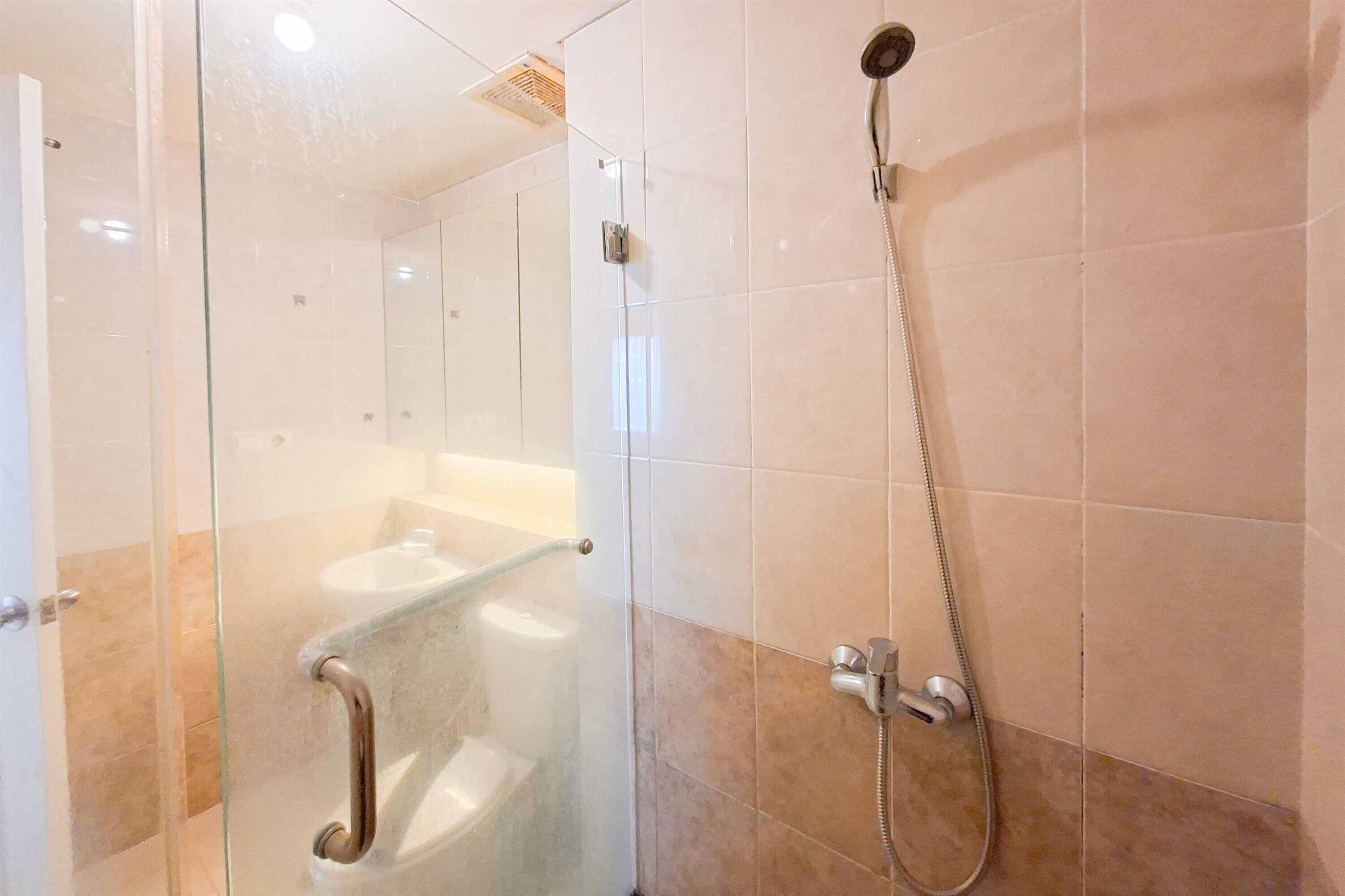 A glass-enclosed shower area with a handheld showerhead and a fixed showerhead.