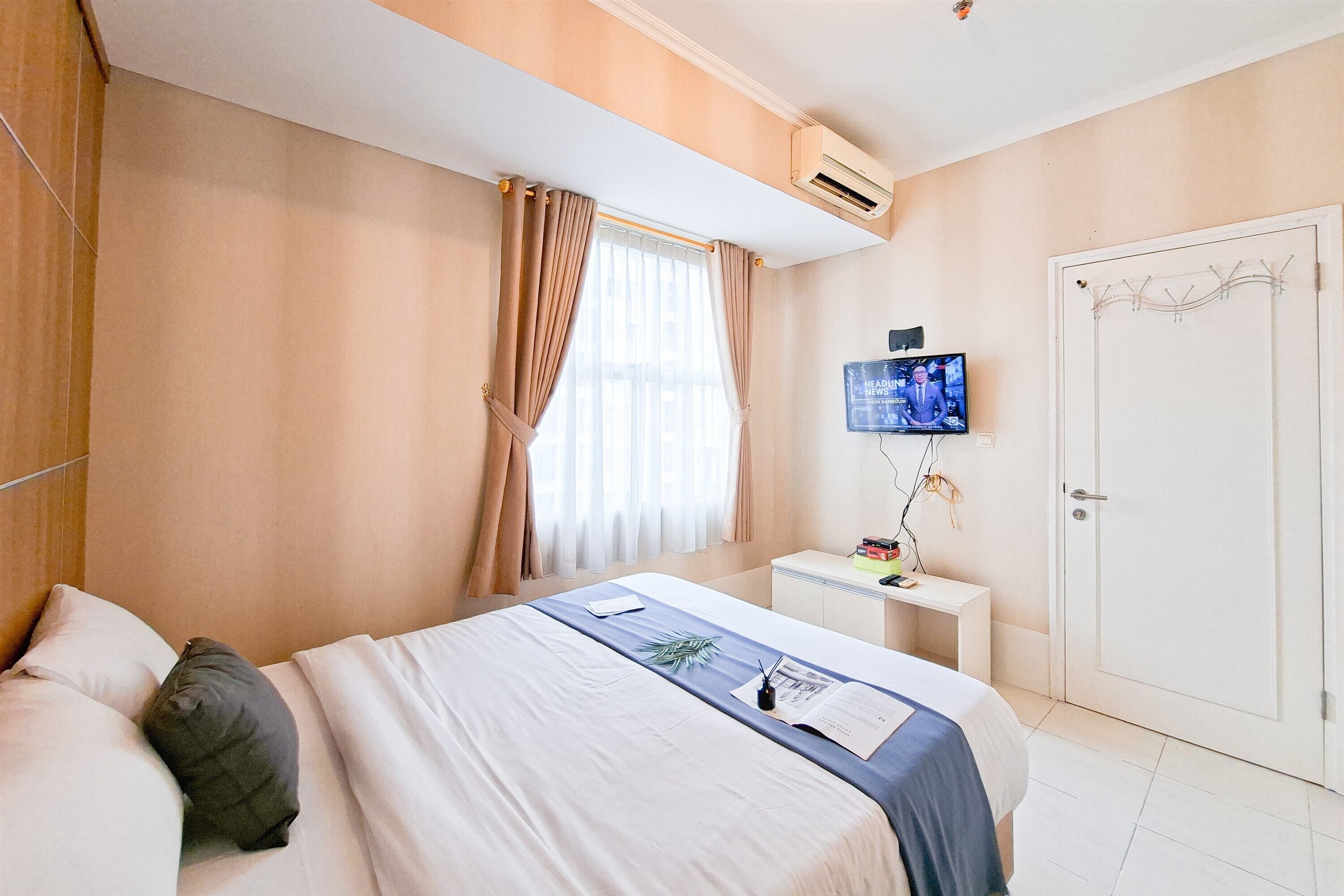 A hotel room with a bed, a nightstand, a TV, and a door.