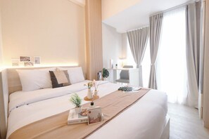 Een moderne hotelkamer met een groot bed, een bureau en een raam met gordijnen.