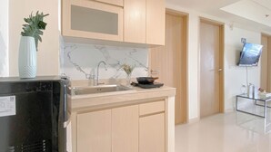 A modern kitchen with light wood cabinets, a marble backsplash, and a built-in sink.