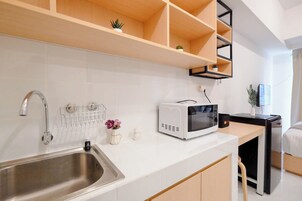 A modern kitchen with a stainless steel sink, a microwave, and wooden shelves above the counter.