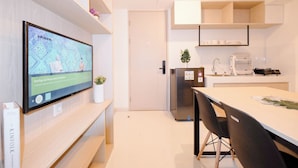 A modern kitchen with a built-in refrigerator, a dining table with chairs, and a TV mounted on the wall displaying a map. - Soft 2Br At Tokyo Riverside Pik 2 Apartment (Teluknaga)