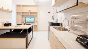 A modern kitchen with a built-in dishwasher, a sink, and a flat-screen TV mounted on the wall. - Soft 2Br At Tokyo Riverside Pik 2 Apartment (Teluknaga)