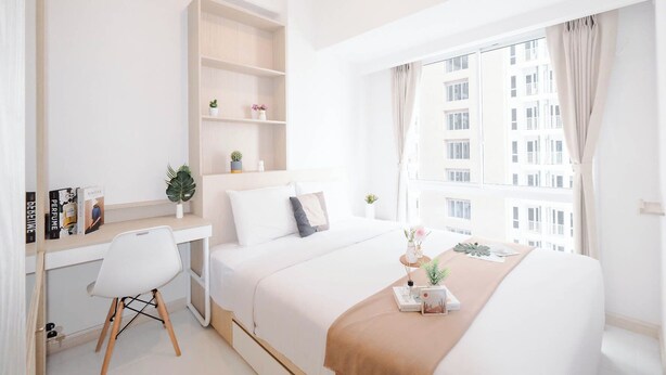 A modern hotel room with a large bed, a desk, and a window with curtains. - Soft 2Br At Tokyo Riverside Pik 2 Apartment (Teluknaga)
