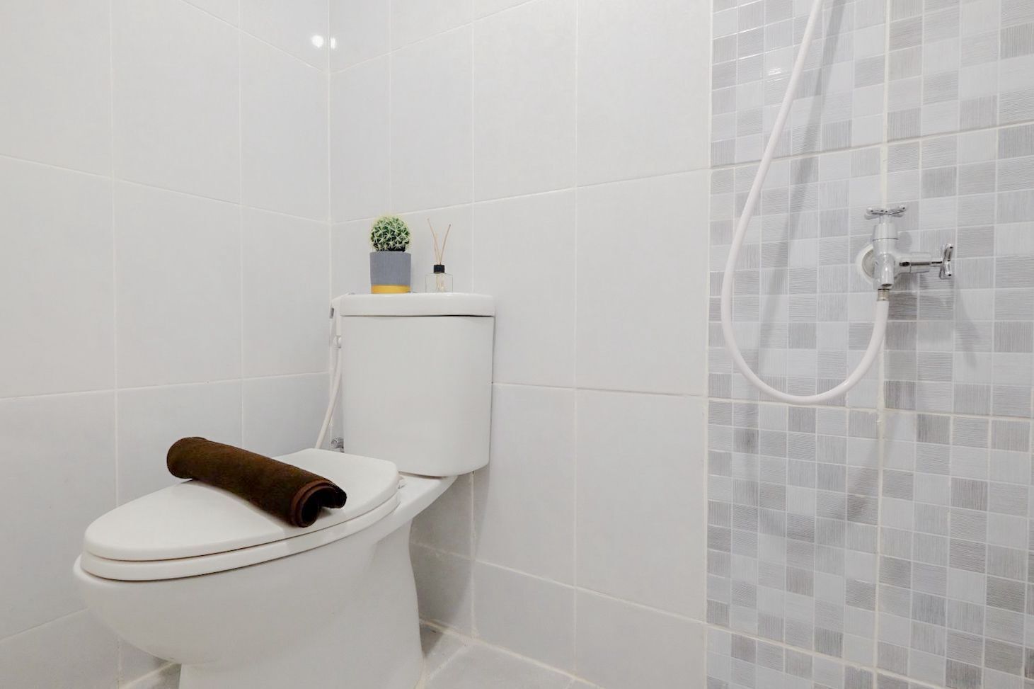Une salle de bain avec des toilettes, une douche et un mur carrelé.