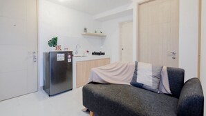 A compact living space with a kitchenette, a sofa, and a refrigerator.