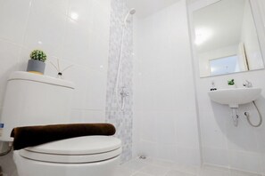 A modern bathroom with a toilet, a shower, and a sink.