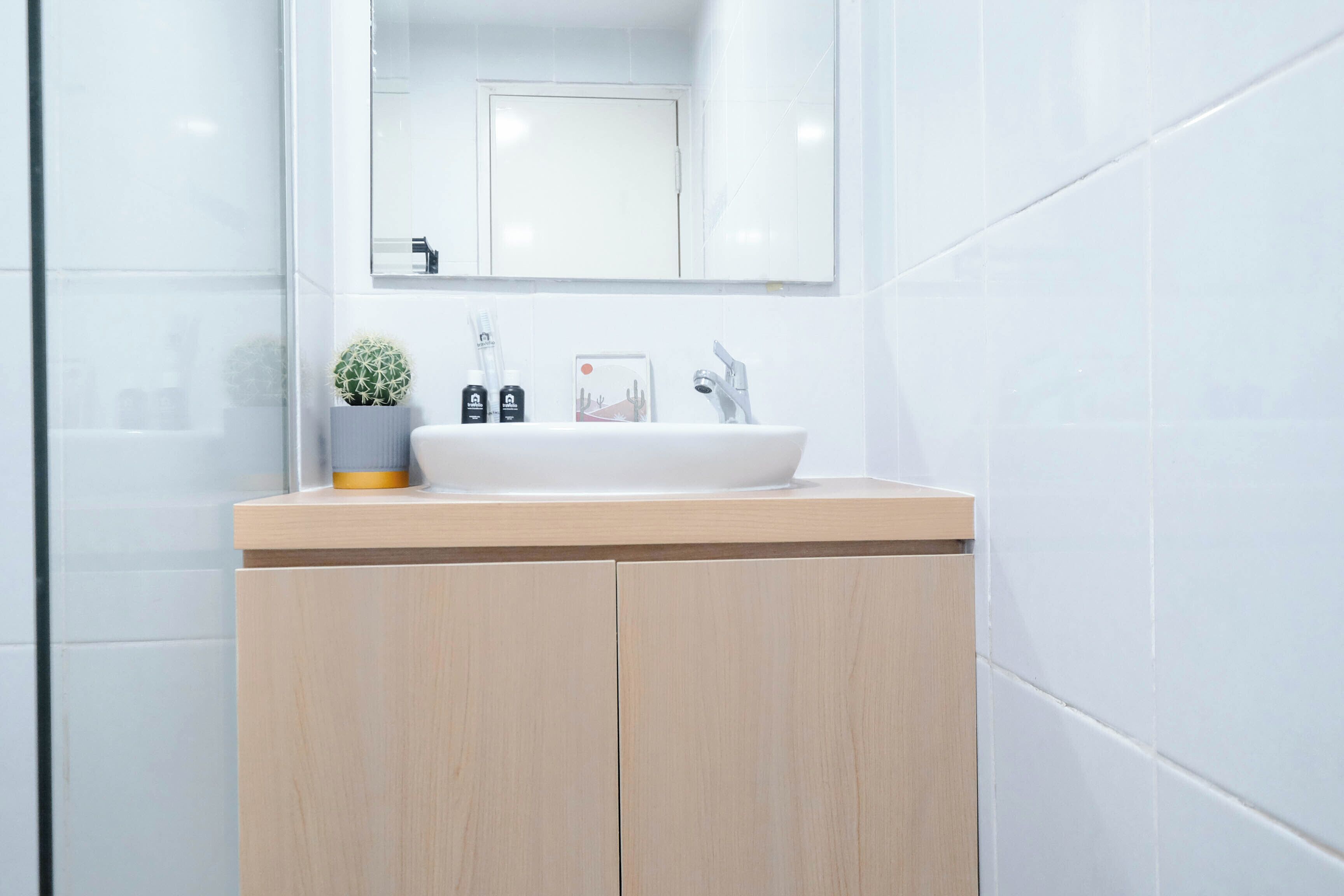 A modern bathroom with a white sink, wooden vanity, and a mirror above the sink.