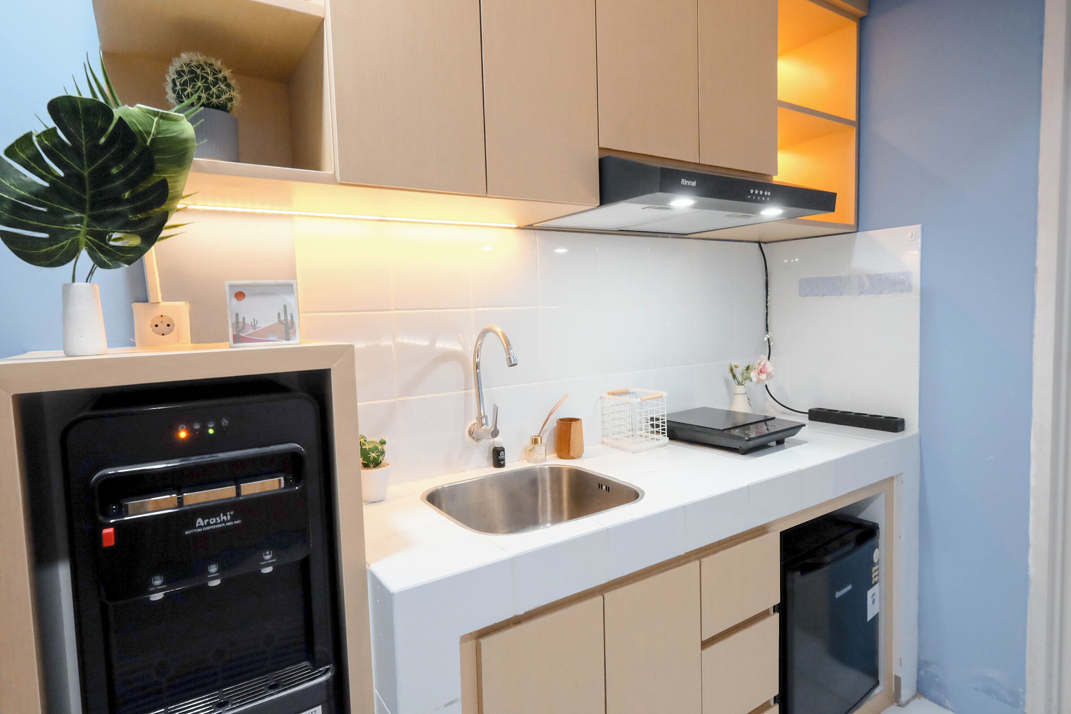 A modern kitchen with a built-in water dispenser, stainless steel sink, and a compact dishwasher.