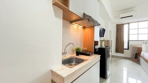 A modern kitchen with a stainless steel sink, a built-in oven, and a flat-screen TV mounted above the counter.