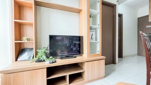 Eine Holzunterhaltungseinheit mit einem Flachbildfernseher, Regalen und einer kleinen Pflanze.