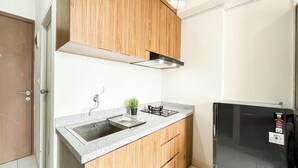 Eine kleine Küche mit Holzschränken, Granit Arbeitsplatten, einem schwarzen Kühlschrank und einem kleinen Topfpflanzen.